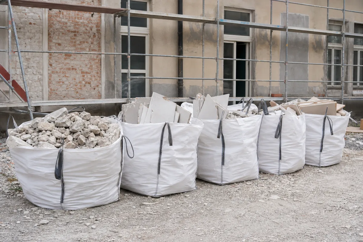 Big bags de gravats et de plâtre triés séparément devant une maison en rénovation