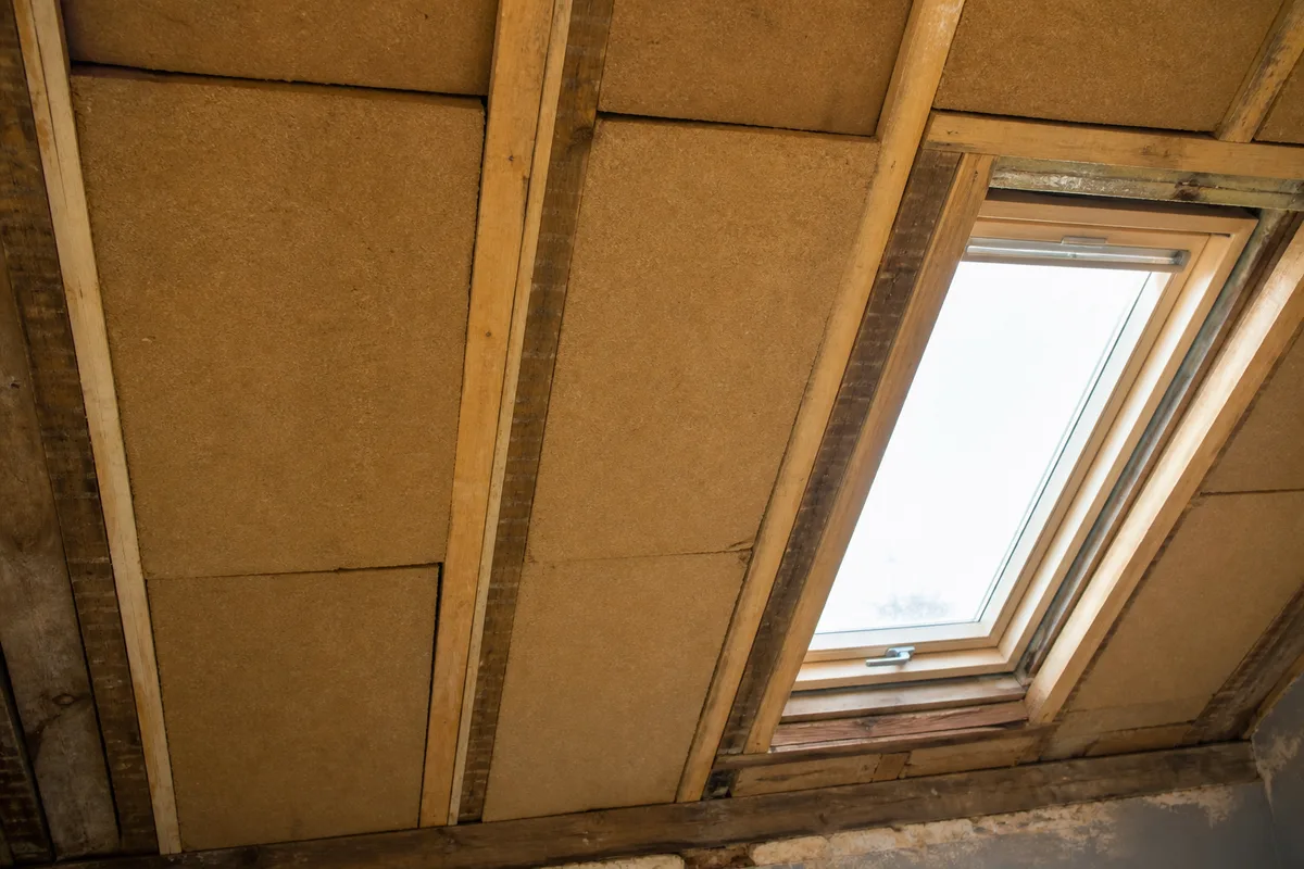 Pose d’un isolant en fibre de bois dense sous la toiture d’une maison en rénovation
