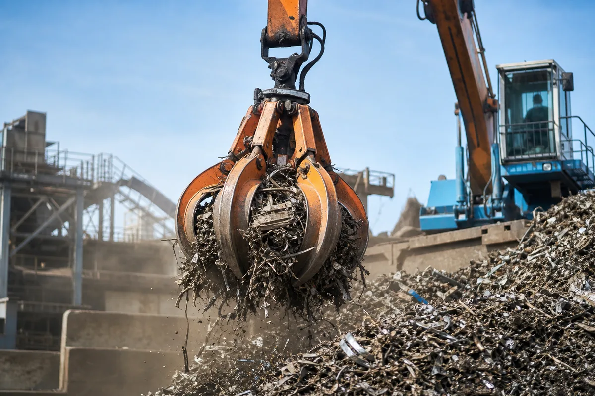 Grappin déplaçant des ferrailles broyées sur une plateforme de recyclage